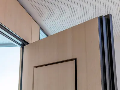 Flächenbündig in die Tür integrierter Verbundlüfter von Uniska, nahtlos ausgeführt in der Echtholzfurnier-Oberfläche bei der Ausgleichskasse Schwyz.