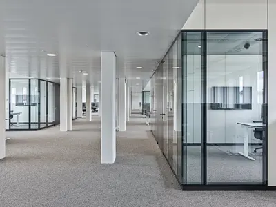 Büro- und Gemeinflächenausbau Georg Fischer AG in Schaffhausen: Grossflächige Structural-Glazing-Trennwände mit präzise ausgeführten 90°-Glasecken gliedern die Arbeitsbereiche, ohne die offene Raumwirkung zu unterbrechen. Die nahezu rahmenlosen Übergänge schaffen klare Sichtachsen und unterstreichen die geradlinige Architektur.