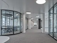 Büro- und Gemeinflächenausbau Georg Fischer AG in Schaffhausen: Spezialgefertigte Structural-Glazing-Rundecken führen die Glastrennwände fliessend durch die Büroflächen. Die präzise gebogenen Glaselemente verbinden Transparenz und anspruchsvolle Geometrie zu einer aussergewöhnlich leichten Raumarchitektur.