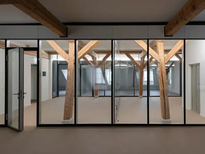 Büroumbau ICT Medien in Basel mit geklebter Doppelverglasung, integriert zwischen den bestehenden Holzbalken des denkmalgeschützten Gebäudes