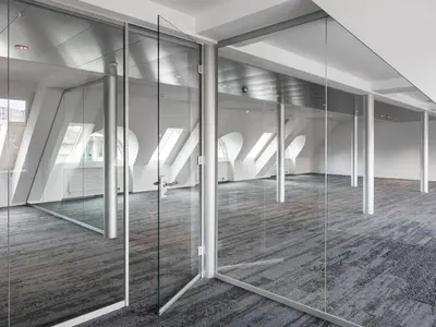 Einscheibenverglasung im Kaufleuten Zürich mit transparenten Glastrennwänden und Glastüren, präzise in die bestehende Dacharchitektur integriert