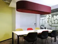 Meetingraum im Office LAB Baslerpark Zürich mit grosser roter Akustikleuchte über dem Besprechungstisch