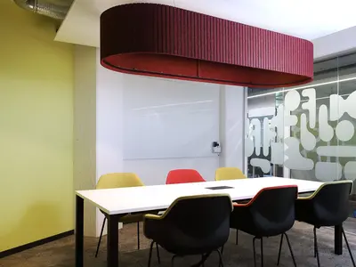 Meetingraum im Office LAB Baslerpark Zürich mit grosser roter Akustikleuchte über dem Besprechungstisch