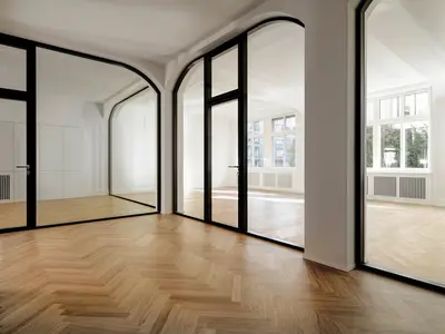 Historische Architektur trifft moderne Glasgestaltung: Die raumhohen Ganzglaswände mit Doppelverglasung folgen dank massgefertigter runder Deckenanschlüsse der bestehenden Gebäudeform und schaffen helle, transparente Räume.