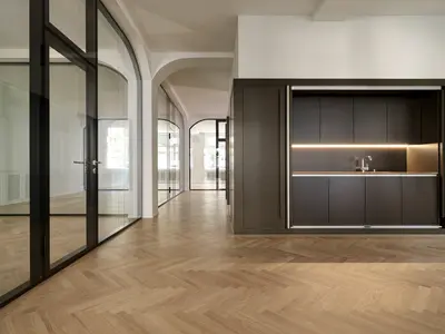 Massgefertigte Ganzglaswände von Uniska integrieren sich präzise in die historische Architektur an der Tödistrasse in Zürich. Doppelverglasung, gerundete Anschlüsse und filigrane schwarze Profile verbinden hohe Transparenz mit einer eleganten Raumgestaltung.