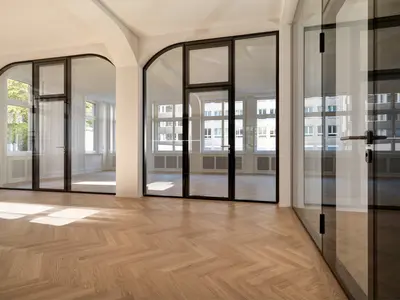 Raumhohe Ganzglaswände mit Doppelverglasung fügen sich passgenau in die historische Architektur an der Tödistrasse in Zürich ein. Die massgefertigten Rundanschlüsse und integrierten Glastüren verbinden den Charakter des Bestands mit einer modernen, lichtdurchfluteten Raumgestaltung.