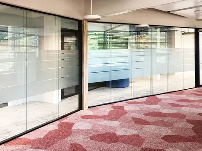 Büroumbau Visana Services AG in Bern: Grosszügige Ganzglaswände schaffen eine helle, offene Bürolandschaft und ermöglichen fliessende Sichtbeziehungen zwischen den unterschiedlichen Arbeitsbereichen. Die Doppelverglasung verbindet transparente Raumtrennung mit funktionaler Abschirmung, während der partiell ausgeführte Sichtschutz gezielt Privatsphäre schafft, ohne die räumliche Offenheit aufzugeben.
