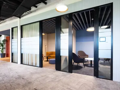 Büroumbau Visana Services AG in Bern: Die Glastrennwände formen klar definierte Rückzugs- und Kommunikationsräume innerhalb der offenen Coworking-Landschaft. Grosszügige Verglasungen erhalten die visuelle Verbindung zwischen den Bereichen, während Sichtschutz und Vorhänge je nach Nutzung unterschiedliche Grade an Privatheit ermöglichen. So entsteht ein wandelbares Raumkonzept zwischen Offenheit, Austausch und konzentriertem Arbeiten.