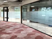 Grossflächige Ganzglaswand mit Sichtschutz und integrierter Tür beim Büroumbau der Visana in Bern.
