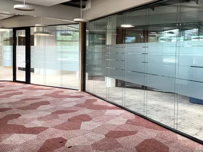 Grossflächige Ganzglaswand mit Sichtschutz und integrierter Tür beim Büroumbau der Visana in Bern.