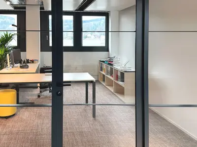 Detail der Loft-Verglasung bei Klima AG in Spreitenbach: Schwarze Rahmenprofile, horizontale Sprossen und die integrierte Glastüre verleihen der Einscheibenverglasung einen prägnanten Industrial Look und schaffen gleichzeitig transparente Büroräume.