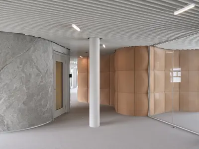 Individuelle Einscheibenverglasung von uniska im Holcim Campus in Zug: Die massgefertigte Glaswand folgt der besonderen Raumgeometrie und schafft einen präzisen Übergang zu den gewölbten Wandflächen – eine moderne Sonderlösung für anspruchsvolle Innenarchitektur.