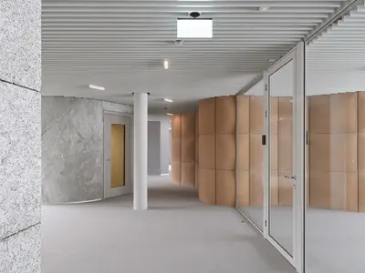 Moderne Einscheibenverglasung im Holcim Campus in Zug: Der präzise Wandanschluss folgt der gewölbten Oberfläche und integriert die Glaswand harmonisch in die aussergewöhnliche Raumarchitektur.