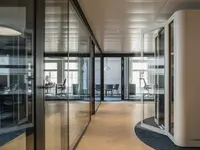 Elegante Doppelverglasung mit raumhohen Ganzglaswänden verbindet transparente Büroarchitektur mit hohem Schallschutz. Die filigranen schwarzen Profile strukturieren die Arbeits- und Besprechungsräume und erhalten gleichzeitig das offene, lichtdurchflutete Raumgefühl.