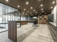 Neubau und Erweiterung Industriehalle Stoss in Walenstadt: Die grossflächige Einscheibenverglasung fügt sich zurückhaltend in das hochwertige Raumkonzept aus Holz, Naturstein und dunklen Akzenten ein. Maximale Transparenz bewahrt die grosszügigen Sichtbeziehungen und lässt die Architektur als Einheit wirken.