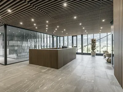 Neubau und Erweiterung Industriehalle Stoss in Walenstadt: Die grosszügige Glastrennwand fügt sich präzise in den repräsentativen Empfangsbereich ein und unterstützt die offene, klare Architektursprache.