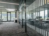 Neubau und Erweiterung Industriehalle Stoss in Walenstadt: Grossflächige Einscheibenverglasungen gliedern die Arbeitsbereiche transparent und lassen Licht und Sichtachsen durch die Büroflächen fliessen. Schwarze Profile und dezente Sichtschutzmarkierungen unterstreichen die klare, moderne Architektur.