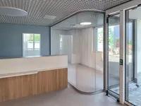 Umbau eines Ärztezentrums mit massgeschneiderter UNISKA Glastrennwand und präzise ausgeführter Rundverglasung im Empfangsbereich